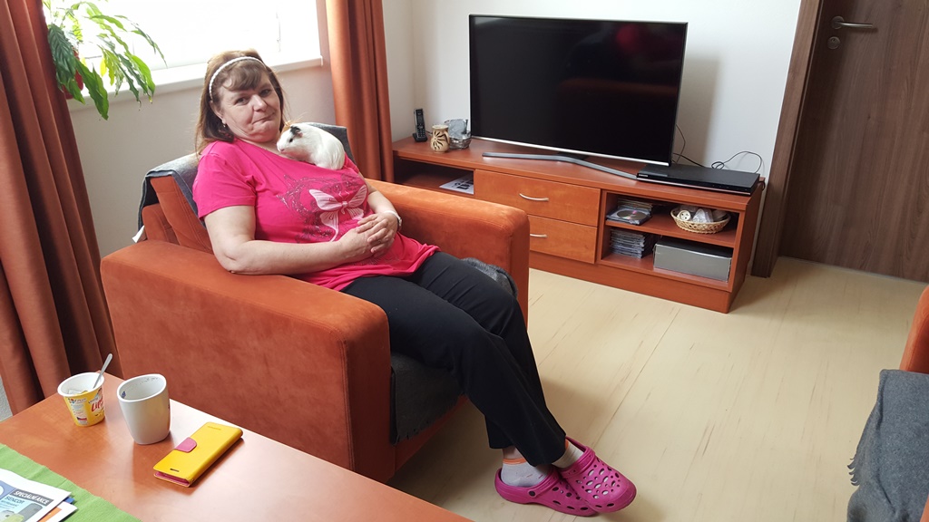 Olinka Hajná je v novém chráněném bytě spokojená. Dokonce už si v Třeboni našla i práci. V záchranné stanici Vydra pomáha s péčí o zvířata