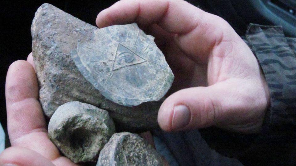 Poklady nalezené na břehu Lipenské přehrady. Olověná zátka se symbolem božího oka se používala při distribuci takzvaného všeléku