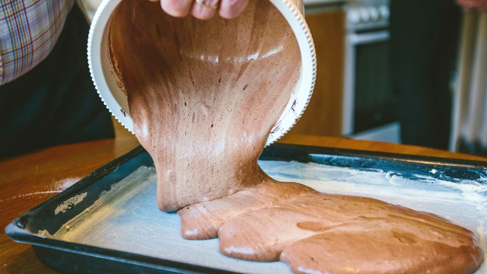 Čokoládovou pěnu na korpus lehce nalijeme do vymazaného pekáče